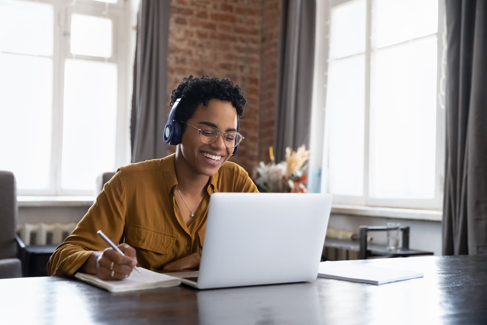 Person in a coaching session on their laptop, taking notes at home